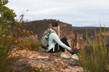 Hiker sitting on cliff edge with sheer mountain views