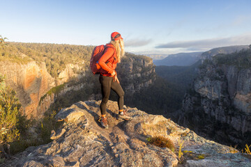 Hiker on a mountain peak looking down a canyon