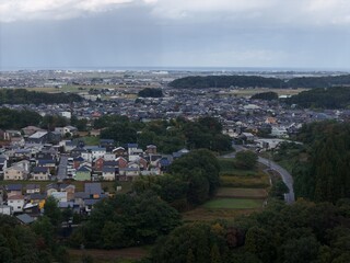 A city view with a lot of houses and trees. The sky is cloudy and the sun is not visible