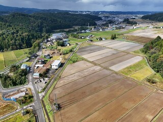 A rural area with a few houses and a few cars. The houses are spread out and the cars are parked in the street