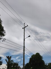 Utility Pole with Power Lines, Insulators, and Streetlight against Cloudy Sky