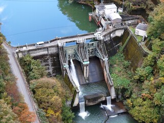 A large body of water with a dam and a bridge over it. The water is green and the bridge is white