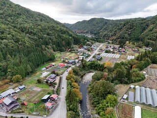 A rural area with a river running through it and houses on the side of the road. The houses are...