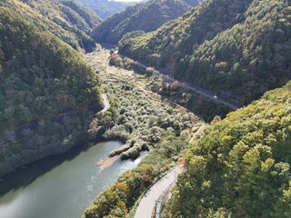 A mountain range with a river running through it. The river is surrounded by trees and the...