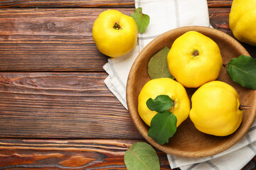 Fresh ripe quinces with leaves on wooden table, flat lay. Space for text