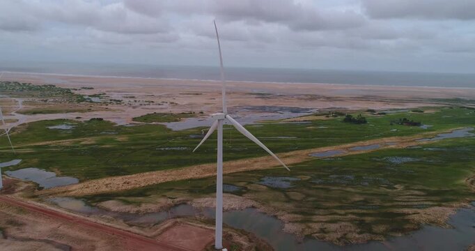 Mar com as dunas e lagoas dos Pequenos Len&ccedil;&oacute;is Maranhenses em Paulino Neves, Maranh&atilde;o, filmado por drone, parque e&oacute;lico, torre e&oacute;lica