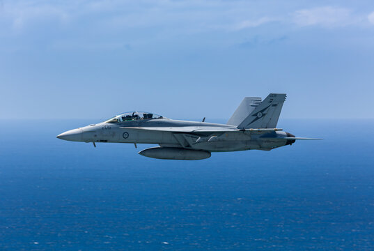 Side view of a FA18 Super Hornet flying at low level over the ocean.