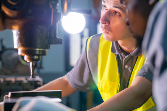 Skilled worker focused on operating machinery in a factory. Wearing high visibility vest and gloves, demonstrating precision, technical ability, safety, and industrial expertise.