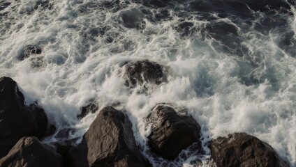 Obraz premium Crashing ocean waves churn against dark, jagged rocks, creating white foam and motion