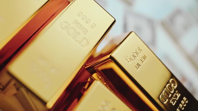 Shiny gold bullions stacked on a background of one hundred dollar bills, representing immense wealth and a valuable safe-haven asset for investment and financial success in a global economy