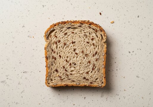 Top view of a healthy whole grain bread slice with flaxseed on a speckled beige surface - Powered by Adobe