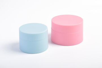 Pink and blue cosmetic jars isolated on a white background.