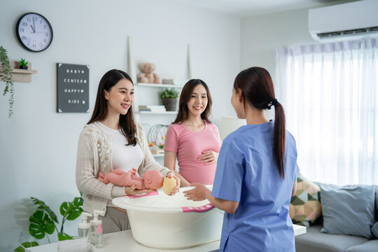 Two pregnant women learn how to bath a baby at maternal health center.  - Powered by Adobe