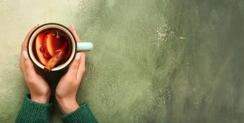 Fototapete Rund Musik Woman's hands holding cup of hot mulled wine on green background with space for text, top view  © Pixel-Shot