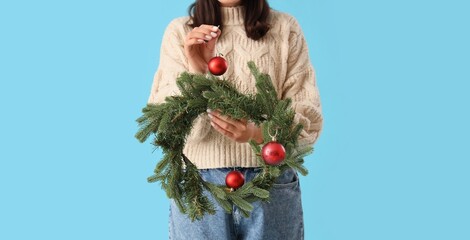 Young woman with Christmas wreath on blue background
