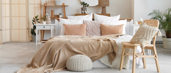 Stylish interior of bedroom with comfortable bed and chair with cushion