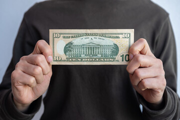 Cropped shot view of woman holding and showing ten American dollar banknotes in hands. The US Dollar is the currency of United States.