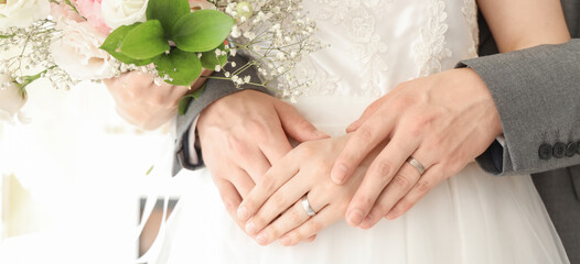 Newlyweds with rings and flowers hugging on their wedding day, closeup
