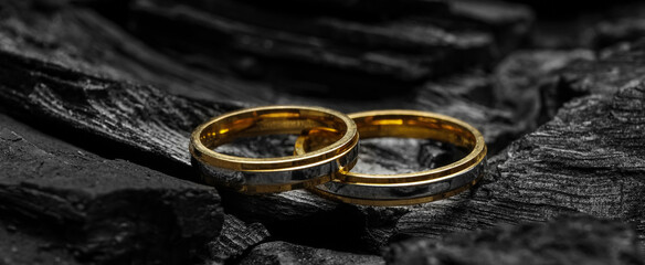 Wedding rings on black charcoal, closeup