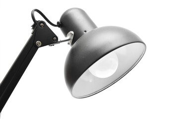 Close-up of a modern black adjustable desk lamp, architect lamp head with illuminated bulb, isolated on a pure white background. Represents work, study, focus, education, and lighting design.