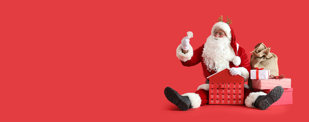 Santa Claus in deer horns with bag, gift boxes and Christmas advent calendar sitting on red background