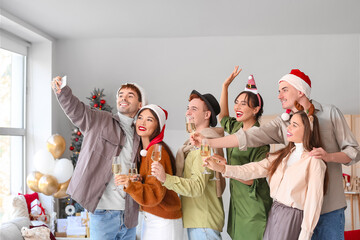 Group of friends with champagne taking selfie at New Year party