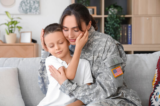 Female soldier with her little son hugging at home