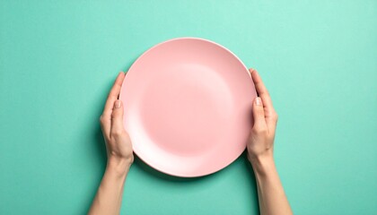 Hands holding empty pink plate, turquoise background, food concept