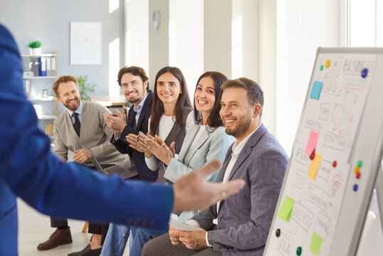 Business coach speaker during successful whiteboard presentation, speaker presenting, consulting, training happy employees client group, leader explaining new company strategy at team meeting workshop