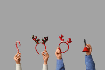 Female hands holding Christmas reindeer horns headbands with bell and candy cane on white background