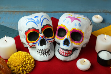 Painted skulls for Mexico's Day of the Dead (El Dia de Muertos) and glowing candles on table