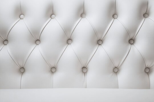Close-up of a white tufted headboard with button details.
