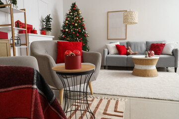 Box with Christmas balls on table in living room interior