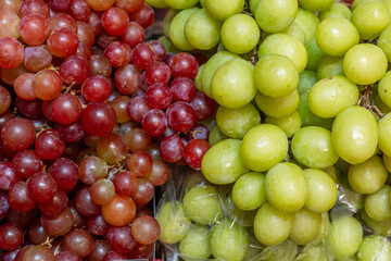 Red and green grapes at the market. Juicy, delicious seasonal fruit. Close-up.