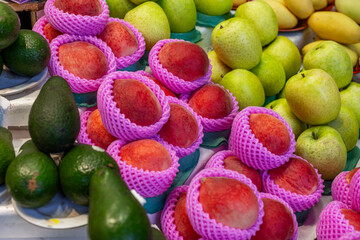 Fresh individually wrapped peaches and apples at the market. Appetizing seasonal fruits. Close-up. Side view.