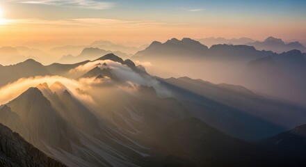 Mountain peaks shrouded in mist illuminated by the setting sun creating a serene and atmospheric landscape perfect for travel and nature themes