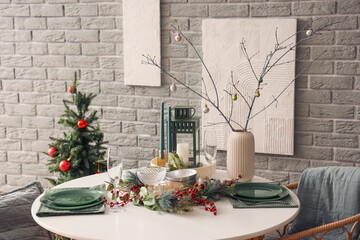 Vase with tree branches and Christmas balls on set dining table in room