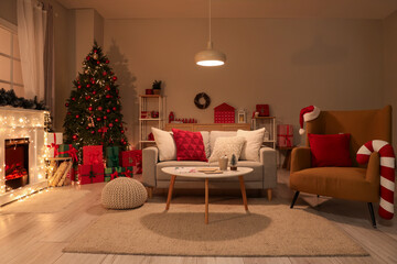 Interior of living room with Christmas tree, sofa and glowing lamp at night