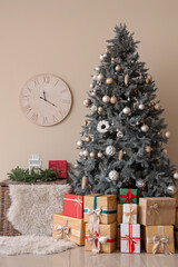 Christmas tree with presents and basket near beige wall in room