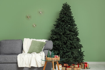 Cozy sofa with cushions, coffee table and Christmas tree with gifts in room