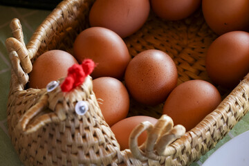 Charming close up of fresh brown eggs inside rustic woven basket. decorative container shaped like chicken creates cozy and natural farm feeling for Easter