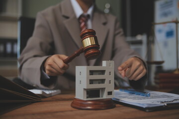 Real Estate Law, Home Insurance, property Tax, Auction and Bidding concepts. small toy house model with gavel justice hammer on desk in courthouse.