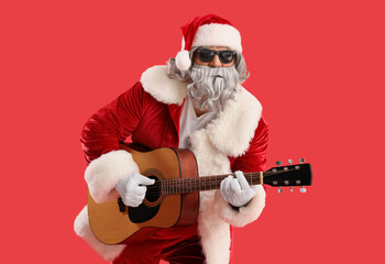 Cool Santa Claus playing guitar on red background