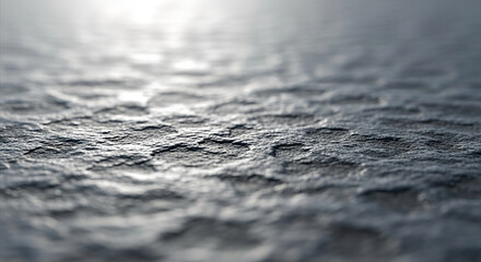 A shallow depth of field shot focusing on a dark, textured, and uneven surface with a subtle sheen, creating an abstract and minimalist background