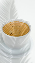 A cup of fresh coffee on a white table and shaded by plants.