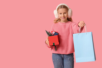 Fototapeta premium Cute girl with shopping bag, gift boxes and credit card on pink background. Christmas celebration