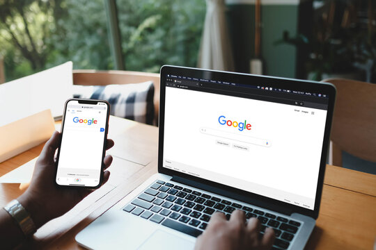 Bangkok, Thailand. October 30, 2025; A person using the Google search engine on both a laptop and a smartphone, demonstrating a responsive web experience.