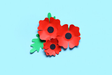 Paper poppy flowers and leaves on blue background. Remembrance Day