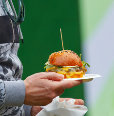 Close-up of a gourmet cheeseburger held by a person at the Karlin Food Festival in Prague.