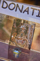Donation box with an image of the Virgen de las Angustias of Granada, showing a religious artwork in golden tones inside a church. faith devotion
